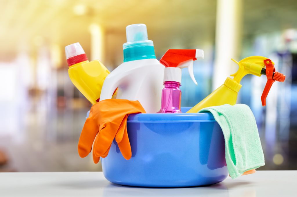 Basket with cleaning items on blurry background used by Cleaning with Krystal in Palm beach, North Broward, Boca Raton, for household cleaning services